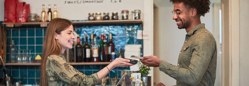 Das Tagesgeldkonto für Kinder und Jugendliche: FVB-FutureFlex 6 Mann und Frau bezahlen mit dem Handy im Café